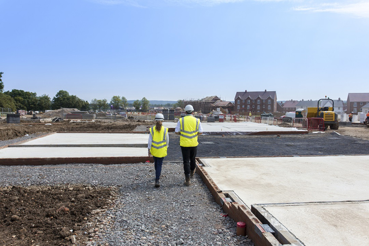 Two people in high visibility jackets on roof top