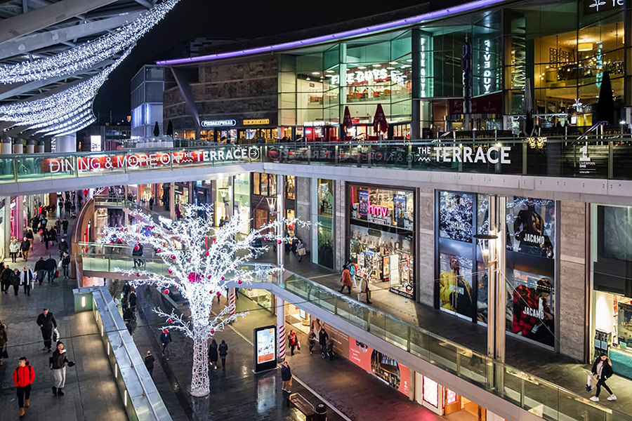 People shopping in Liverpool ONE with a tree covered in lights in the centre