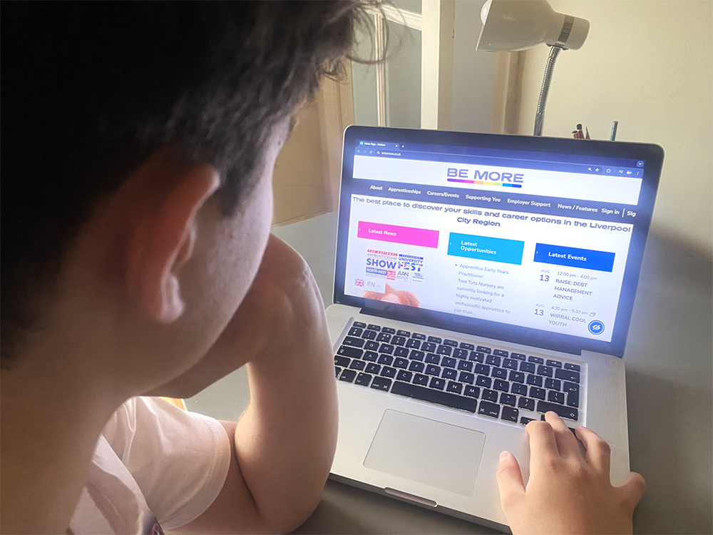 Young male pictured working on laptop displaying be more website