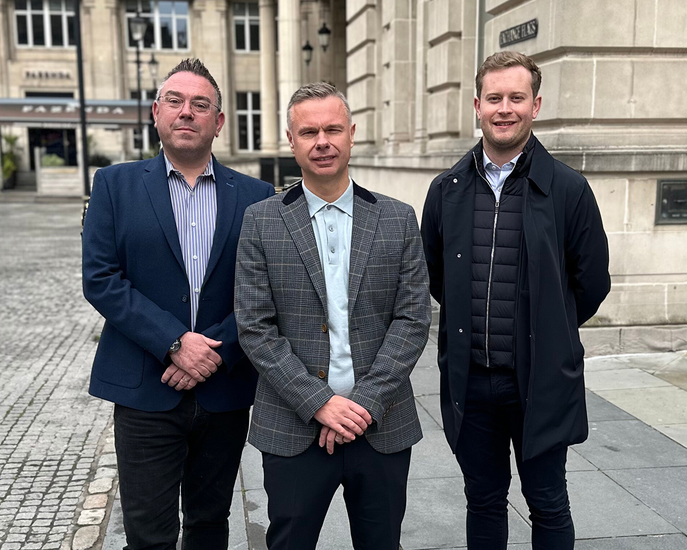 Three males stood in public area.