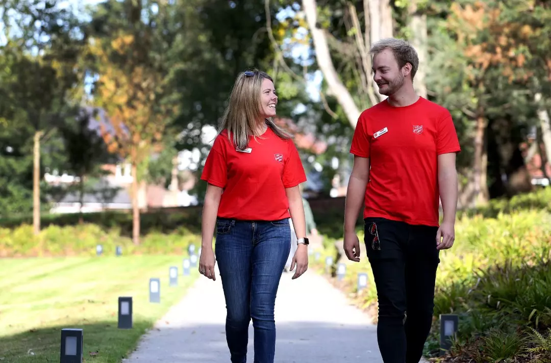 Male and female volunteers wearing red t-shirts walking in park