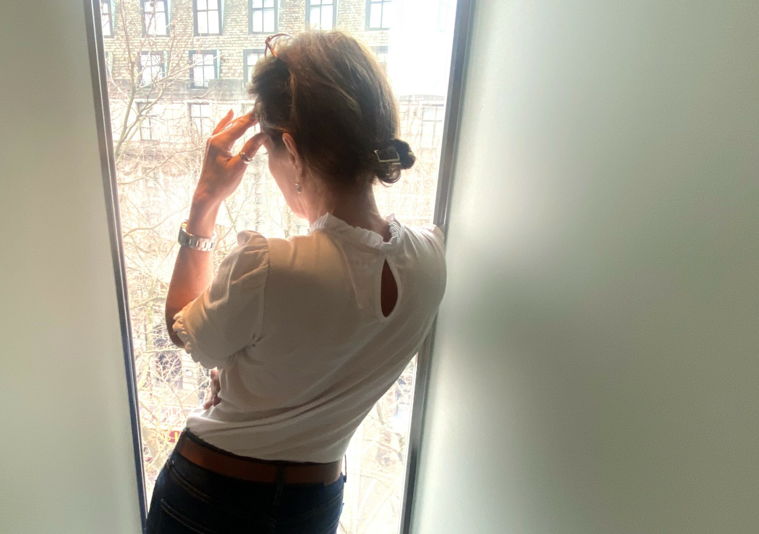 Young female stood by window looking out