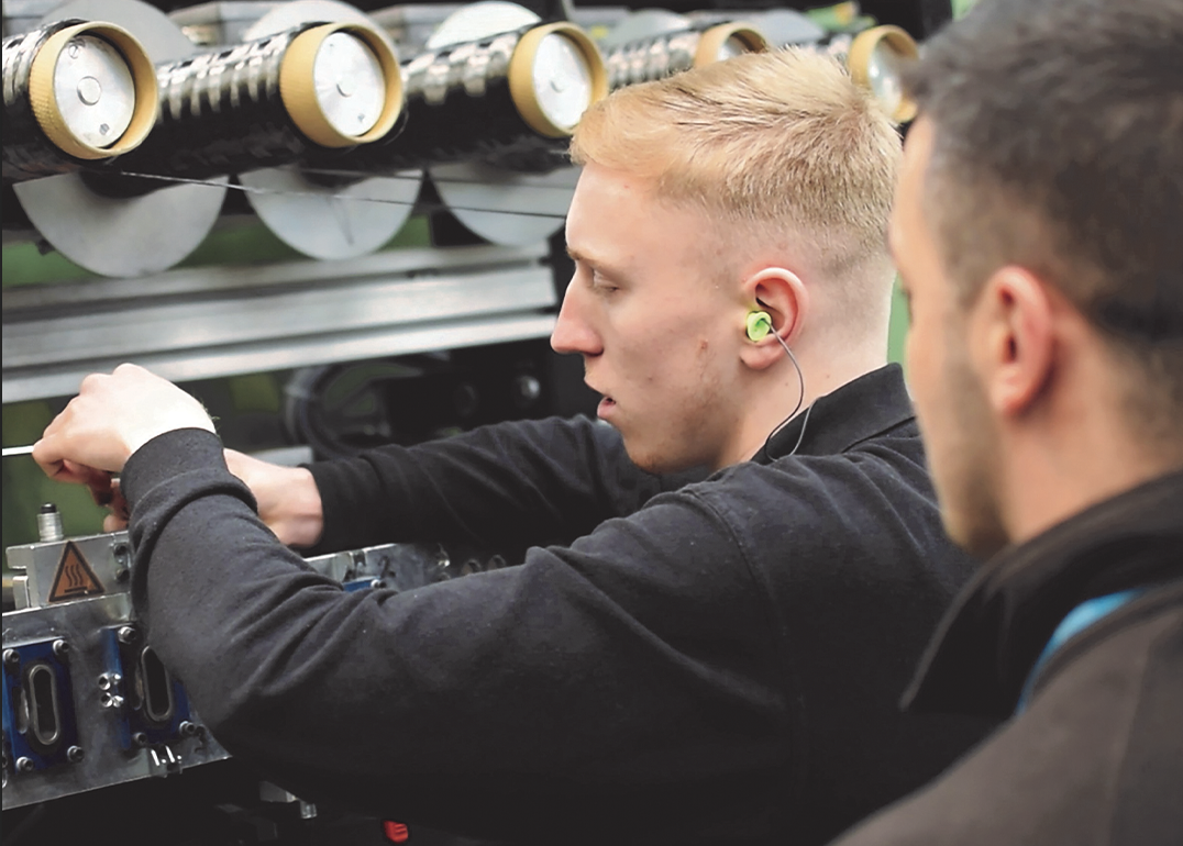 Young male engineering apprentice being mentored in the workplace