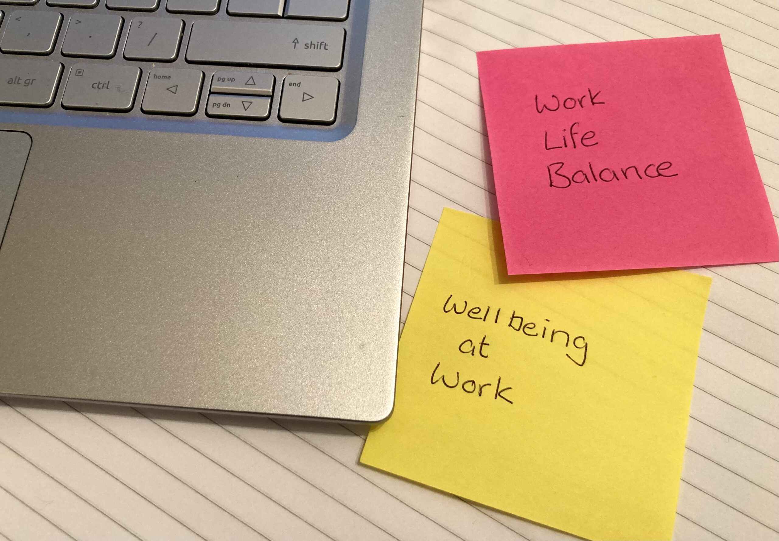 Image of post it notes in fluorescent colours next to lap top promoting work life balance and wellbeing at work